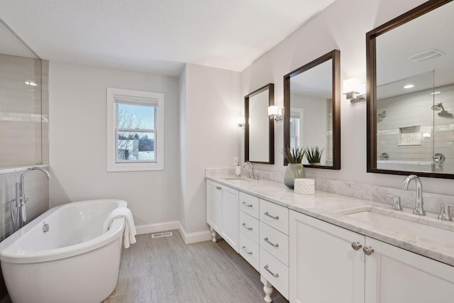 bathroom featuring plus walk in shower, hardwood / wood-style floors, vanity, and a textured ceiling