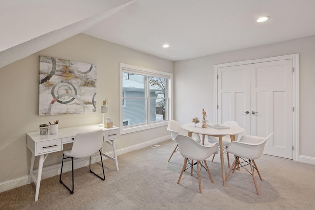 dining area with light colored carpet and lofted ceiling