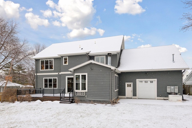 snow covered rear of property featuring a garage