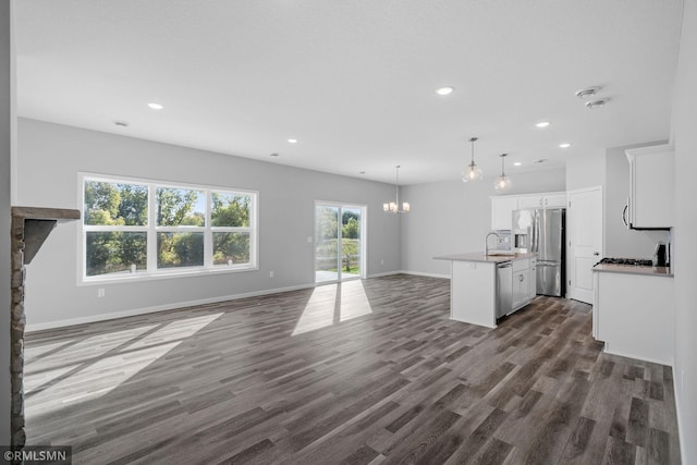 kitchen featuring dark hardwood / wood-style floors, pendant lighting, a kitchen island with sink, appliances with stainless steel finishes, and white cabinets