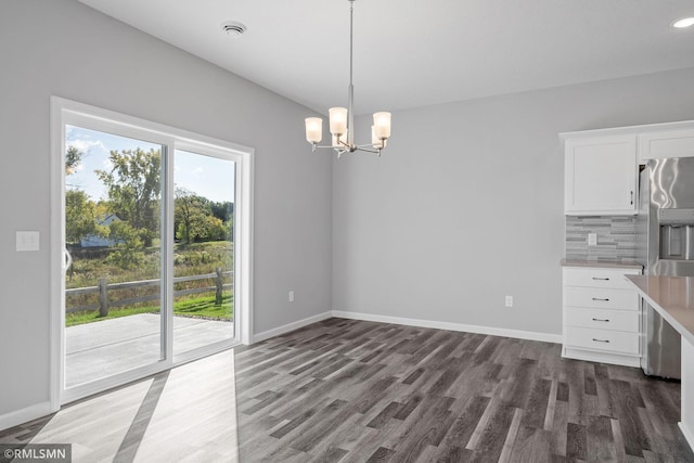 unfurnished dining area with dark wood-type flooring and a chandelier