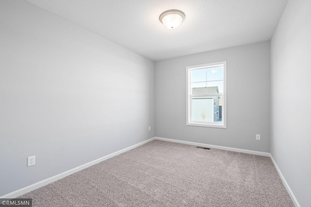 carpeted empty room with a textured ceiling