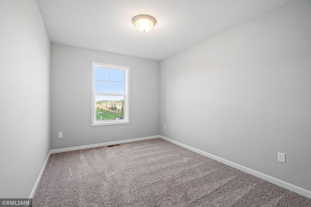 carpeted empty room featuring a textured ceiling