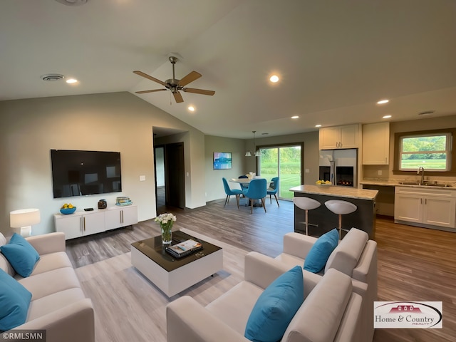 living room with light wood-type flooring, ceiling fan, and sink