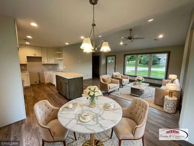 dining area featuring ceiling fan with notable chandelier and dark hardwood / wood-style flooring