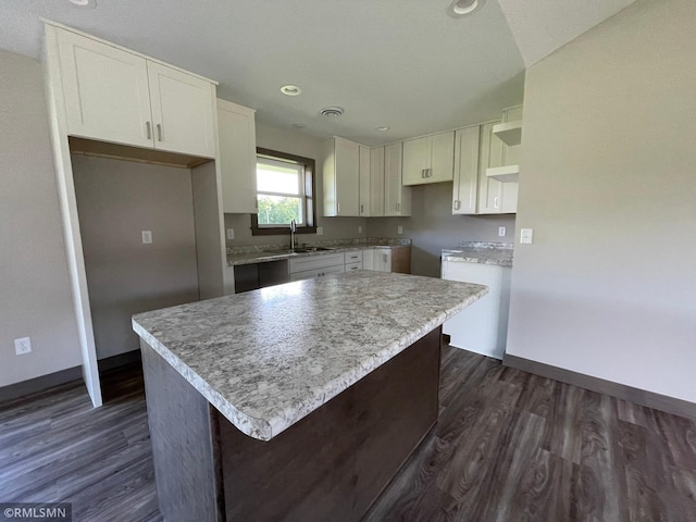 kitchen with dark hardwood / wood-style flooring, white cabinetry, a kitchen island, and sink