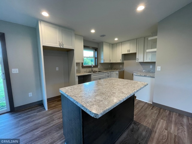 kitchen with white cabinetry, sink, a kitchen island, and dark wood-type flooring