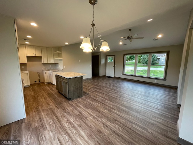 kitchen with ceiling fan, a center island, hanging light fixtures, dark hardwood / wood-style floors, and white cabinets