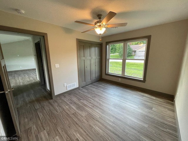 unfurnished bedroom with ceiling fan, a closet, and dark wood-type flooring