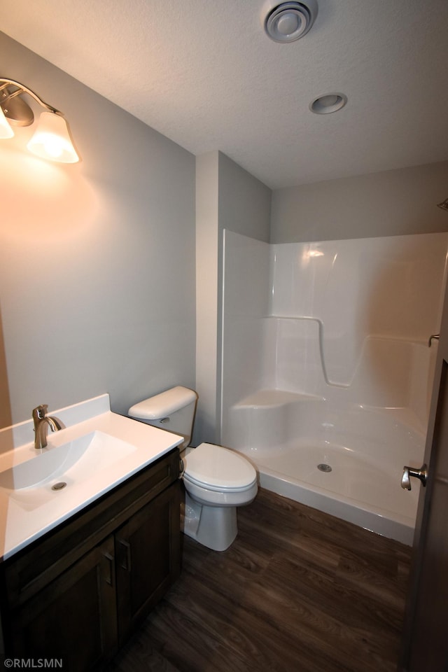 bathroom featuring hardwood / wood-style floors, toilet, a shower, and vanity