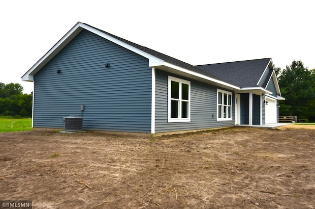 view of property exterior with central AC unit and a garage