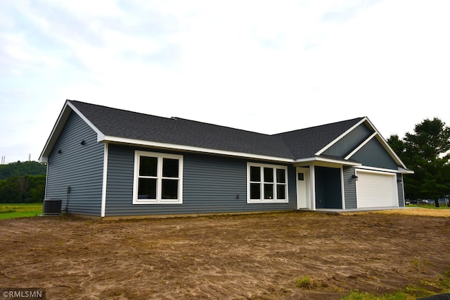 ranch-style home with a garage and central AC unit