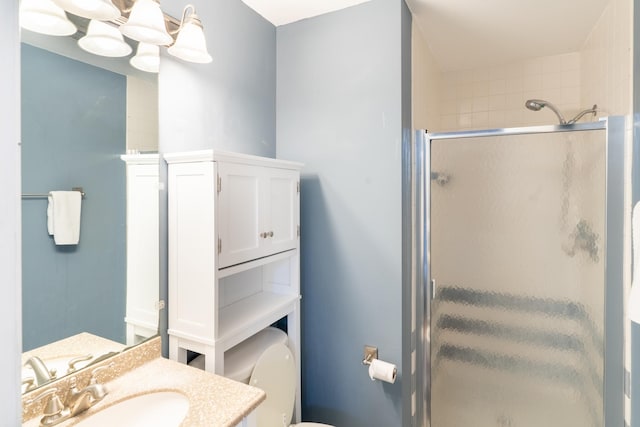 bathroom with vanity, toilet, a notable chandelier, and a shower with shower door