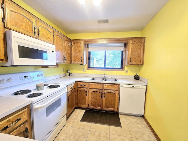 kitchen featuring light tile patterned floors, white appliances, and sink