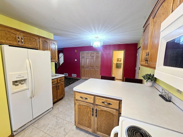 kitchen with an inviting chandelier, kitchen peninsula, a textured ceiling, white appliances, and light tile patterned floors