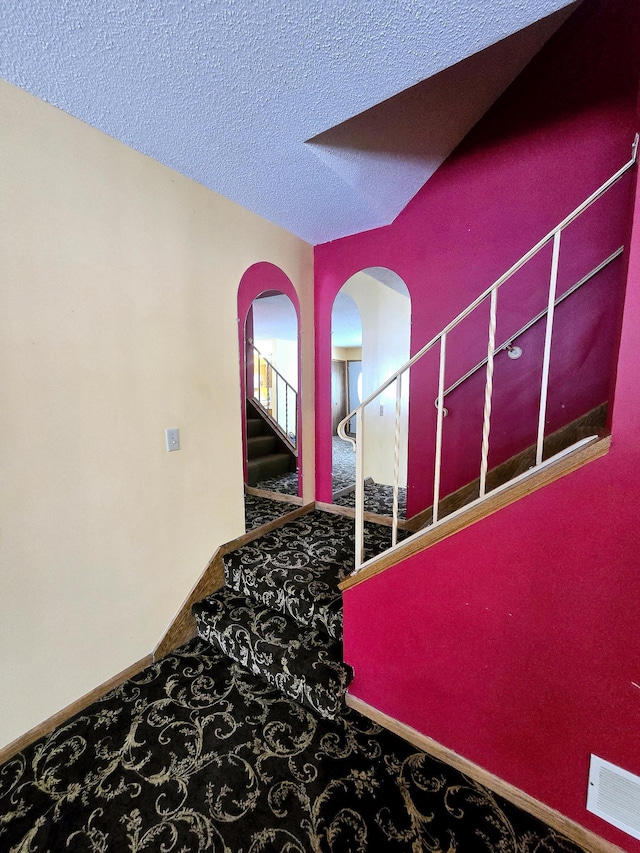 stairway with carpet and a textured ceiling