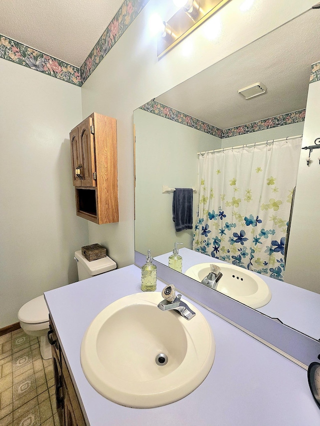 bathroom with curtained shower, vanity, a textured ceiling, and toilet