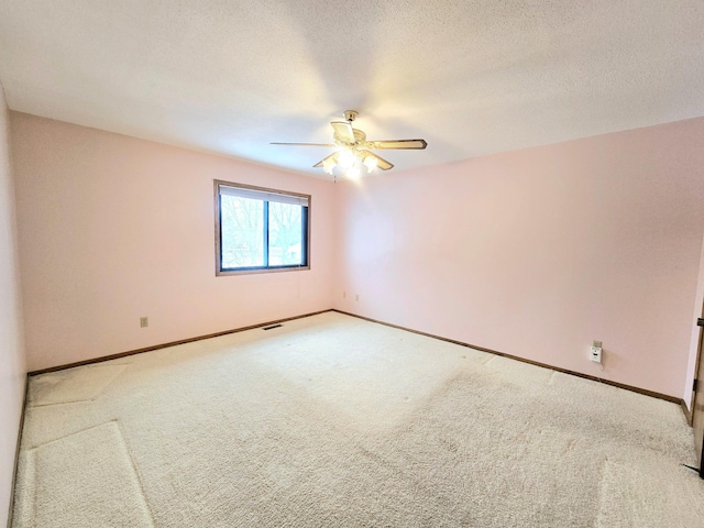 unfurnished room featuring ceiling fan, light colored carpet, and a textured ceiling