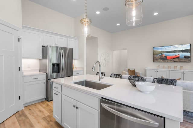 kitchen with an island with sink, white cabinets, sink, and stainless steel appliances