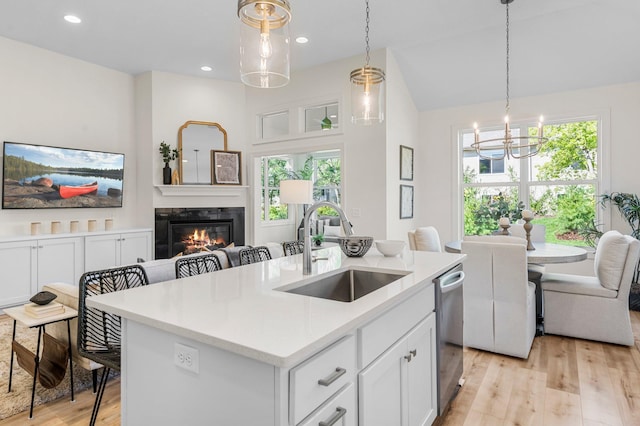 kitchen featuring white cabinetry, an island with sink, sink, hanging light fixtures, and stainless steel dishwasher