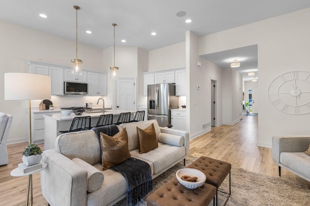 living room with sink, a high ceiling, and light hardwood / wood-style floors