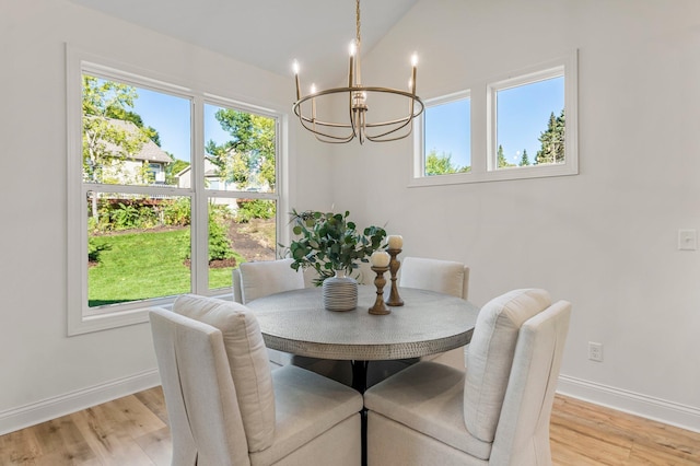 dining room with light wood-type flooring, lofted ceiling, plenty of natural light, and a notable chandelier