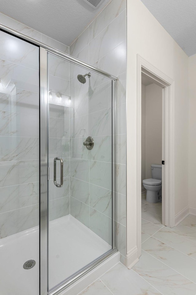 bathroom featuring a textured ceiling, toilet, and walk in shower