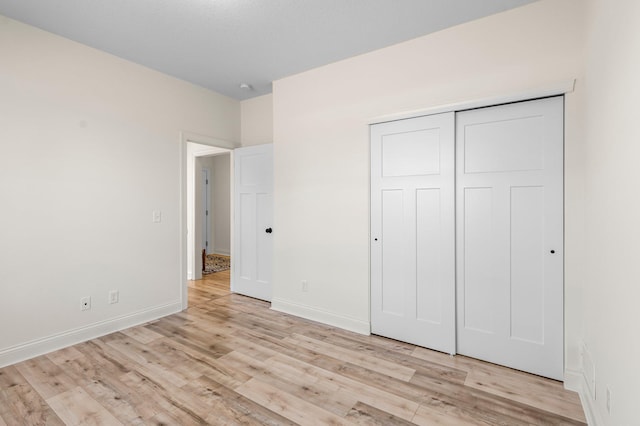 unfurnished bedroom with light wood-type flooring and a closet