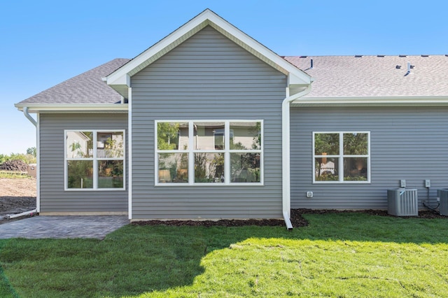 rear view of property with cooling unit, a yard, and a patio