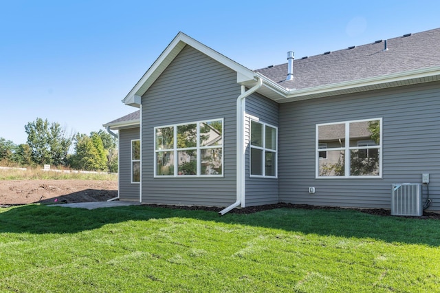 back of house with cooling unit and a yard