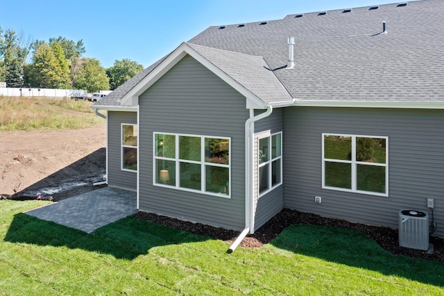 back of property with a lawn, central air condition unit, and a patio