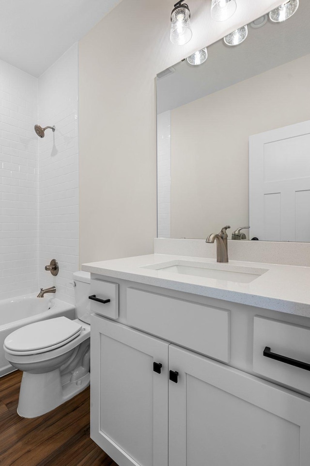 full bathroom with toilet, tiled shower / bath, hardwood / wood-style flooring, and vanity