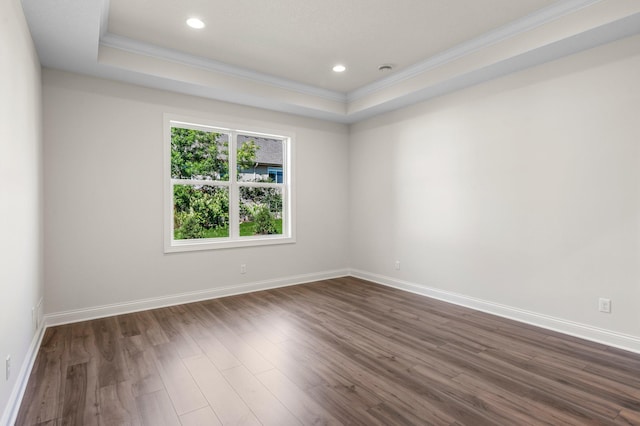 unfurnished room featuring dark wood-type flooring, ornamental molding, and a tray ceiling