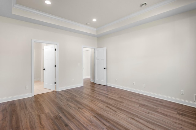 unfurnished bedroom with wood-type flooring, a tray ceiling, and crown molding