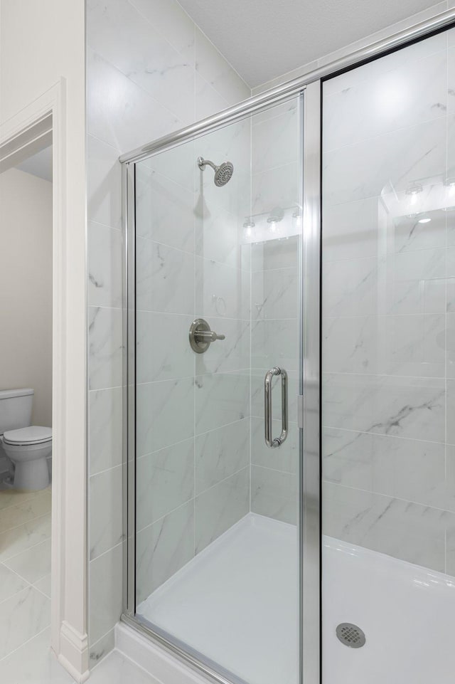 bathroom featuring toilet, tile patterned flooring, and a shower with shower door