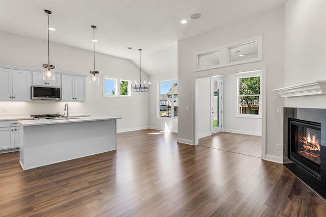 kitchen featuring hanging light fixtures, white cabinets, and a center island with sink