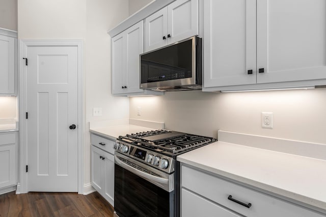 kitchen with dark hardwood / wood-style floors, stainless steel appliances, and white cabinetry