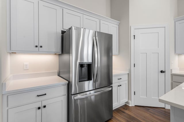 kitchen with dark wood-type flooring, white cabinets, and stainless steel fridge