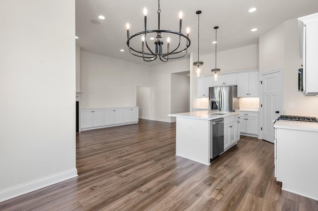 kitchen with stainless steel fridge with ice dispenser, white cabinets, hanging light fixtures, and a kitchen island with sink