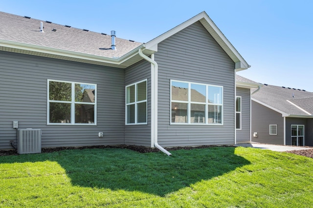 rear view of property featuring a lawn and central air condition unit