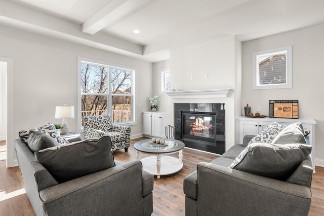 living room featuring wood-type flooring, a fireplace, and beamed ceiling