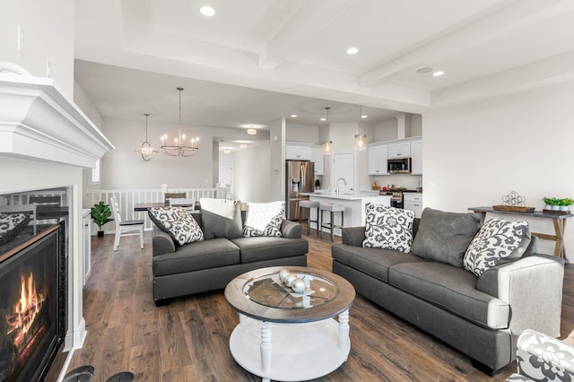 living room featuring a high end fireplace, sink, dark hardwood / wood-style floors, a chandelier, and beam ceiling