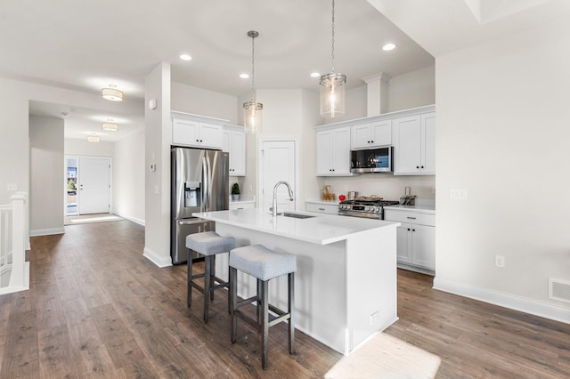 kitchen with white cabinets, stainless steel appliances, an island with sink, sink, and a kitchen breakfast bar