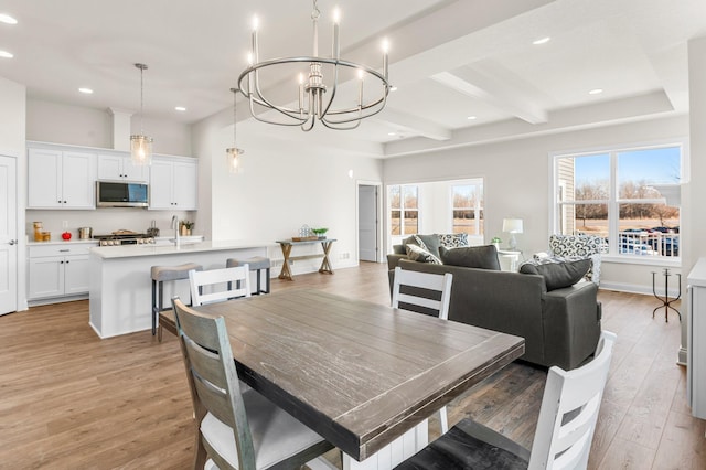 dining space featuring sink, beamed ceiling, a chandelier, and hardwood / wood-style flooring