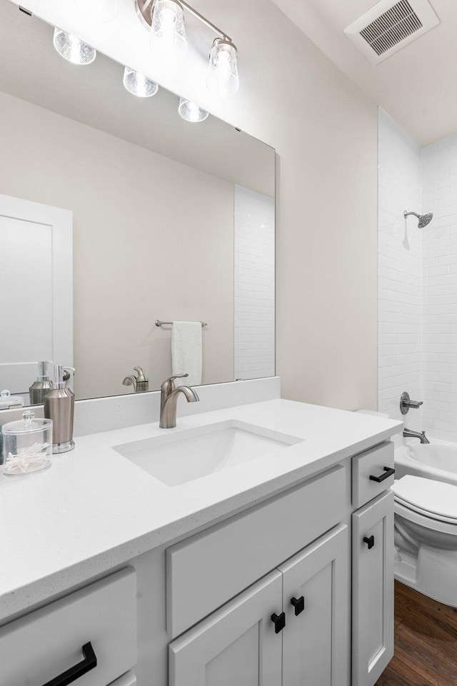 full bathroom with toilet, vanity, tiled shower / bath combo, and hardwood / wood-style flooring