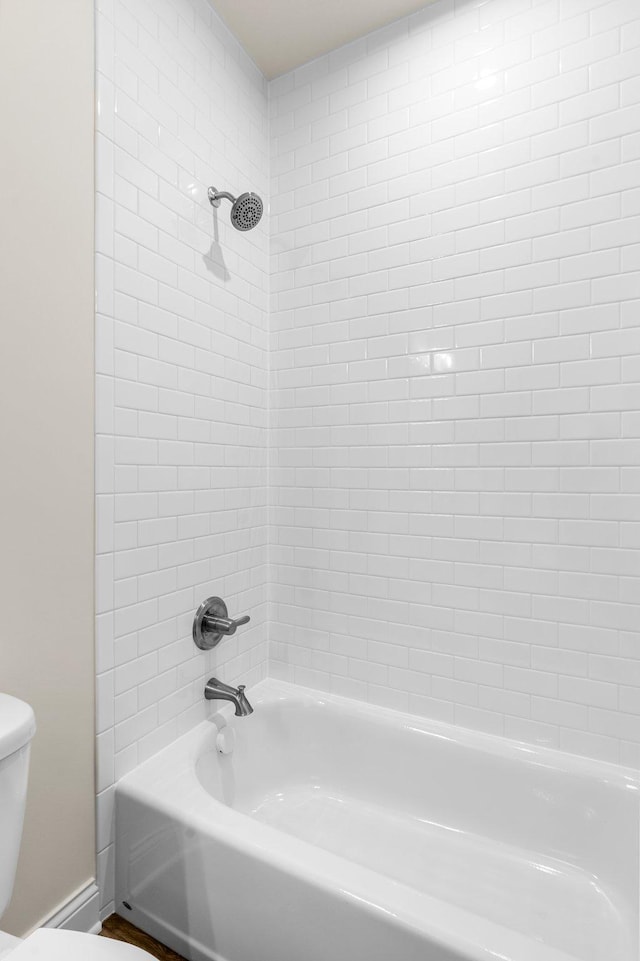 bathroom featuring toilet and tiled shower / bath