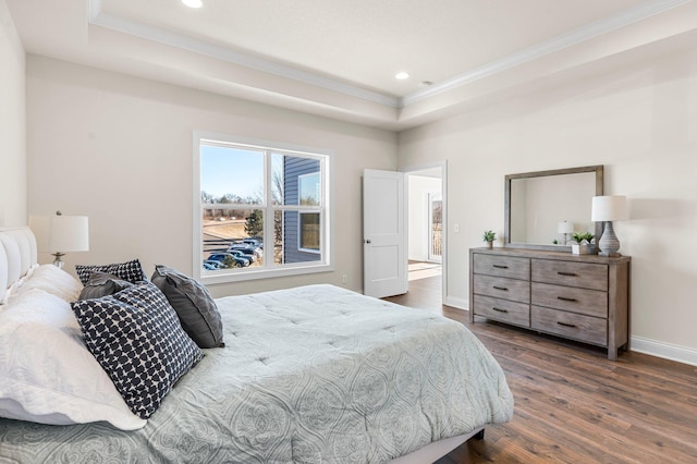 bedroom with dark wood-type flooring, ornamental molding, and a raised ceiling