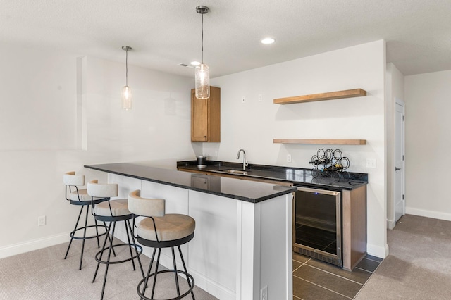 kitchen featuring pendant lighting, wine cooler, sink, kitchen peninsula, and a breakfast bar area