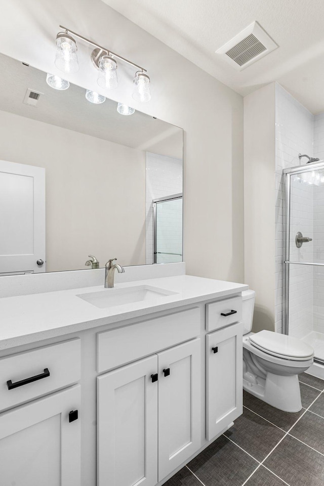 bathroom featuring a shower with shower door, vanity, tile patterned flooring, and toilet