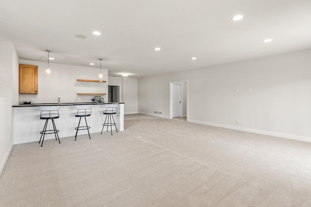 kitchen with light brown cabinets, light carpet, sink, hanging light fixtures, and a breakfast bar